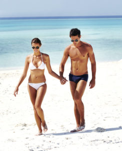 Attractive young couple walking on the beach with a seplane floating in the background